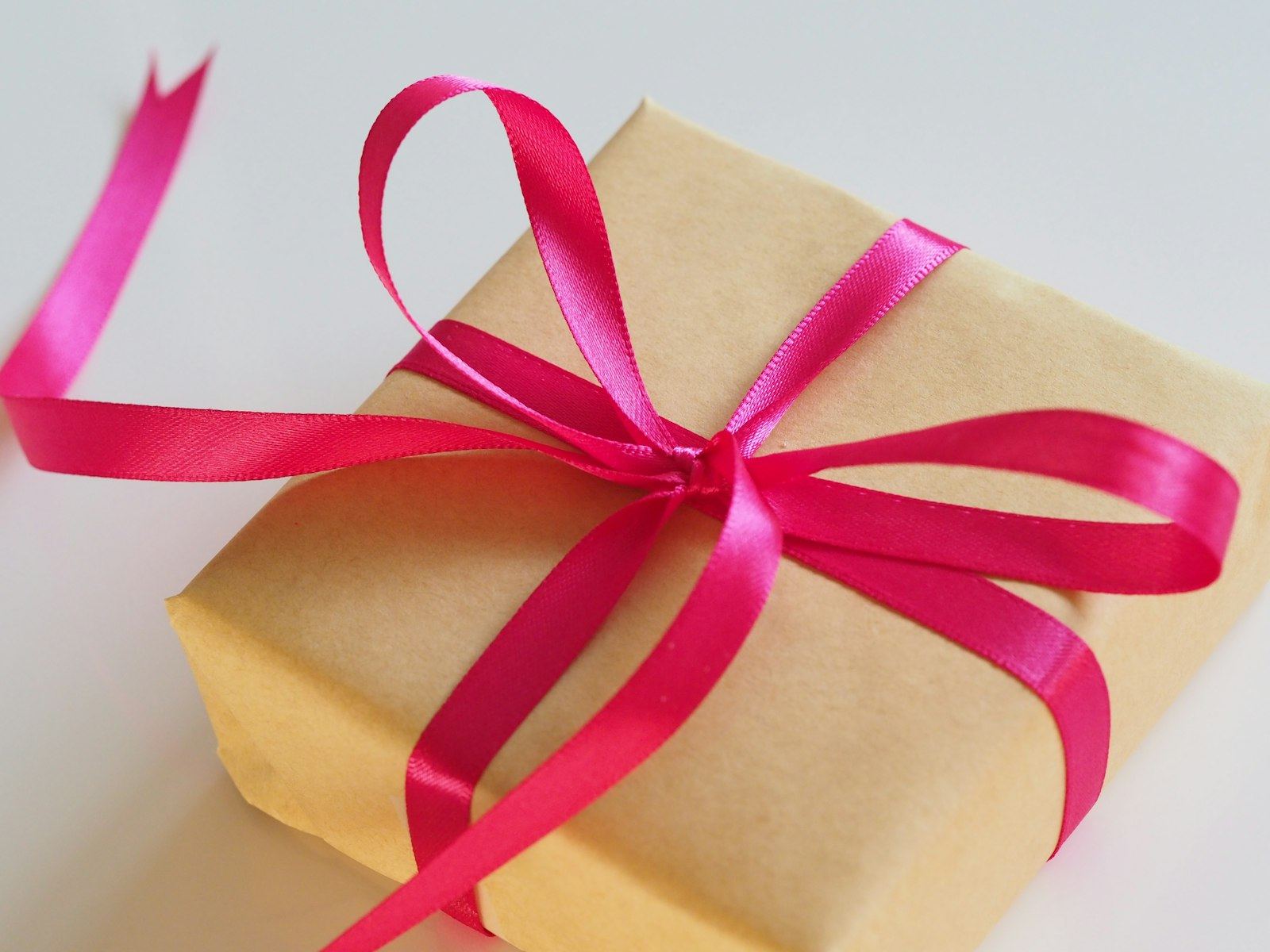 A kraft paper gift tied with a pink satin ribbon